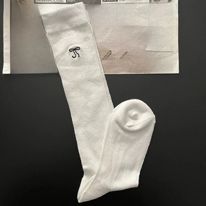 Detail of white cotton calf socks featuring delicate black bow embroidery and knit texture