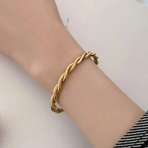 Close-up of 18K gold twisted rope bangle with a polished finish on model's wrist