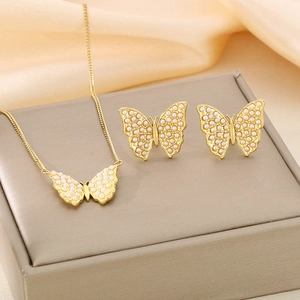Close-up of golden butterfly jewelry set with faux pearls on beige silk fabric