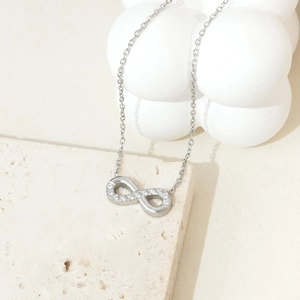 Macro detail of infinity pendant necklace with sparkling cubic zirconia on stone background