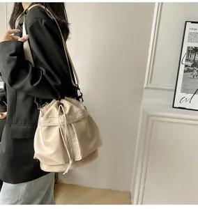 Detail of beige nylon drawstring bucket bag with adjustable wide strap and black buckles