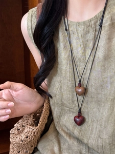 Close-up of wooden heart pendants on woven ropes featuring a retro ethnic style necklace