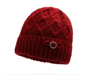 Detail of dark red knit hat with textured diamond pattern and rhinestone bow accent
