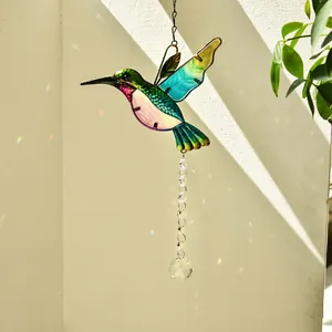 Coloured hummingbird suncatcher with crystal prism reflecting rainbow on beige wall