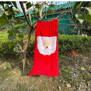 Red velvet Christmas gift bag with Santa Claus embroidery hanging on a tree branch