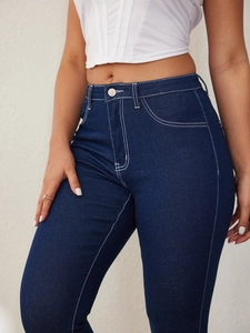 Detail of dark blue skinny jeans featuring contrast white stitching and metal button