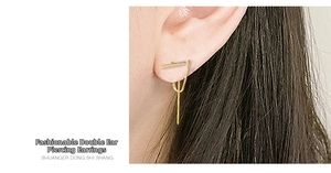 Macro shot of gold double piercing tassel earrings with minimalist metal box chains