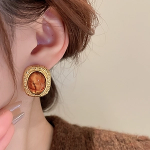 Close-up of model wearing retro gold metal resin earrings with amber stone detail