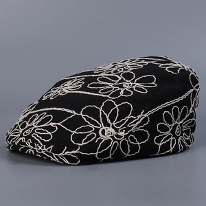 Detailed close-up of white floral embroidery patterns on a black vintage ivy cap
