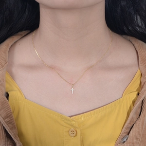 Minimalist sterling silver gold cross pendant necklace with sparkling cubic zirconia on a model