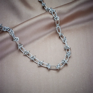 Chunky silver link chain necklace in industrial style on champagne silk fabric background
