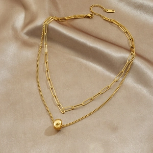 Layered gold chain necklace with geometric round pendant on elegant champagne satin fabric