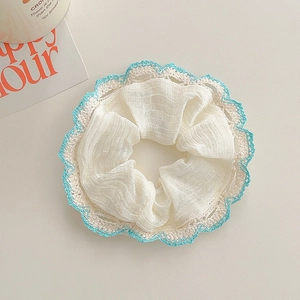 Detail of white scrunchie with blue crochet lace trim and pleated texture fabric