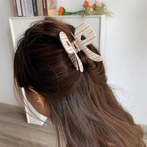Detail of butterfly hair claw clip with pink hearts and stripes on female model