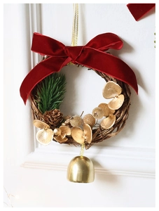 Detail of Christmas wreath with red velvet bow, pine cone and golden bell ornament