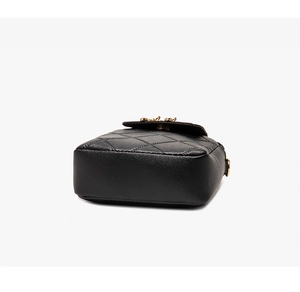 Detail view of the black quilted leather phone bag showing stitching and golden hardware