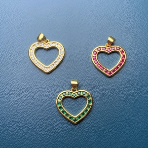 Detailed macro shot of three gold heart pendants with red, green and white crystal stones