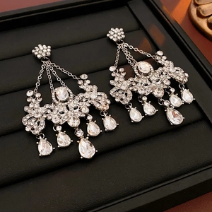 Macro detail of silver floral chandelier earrings with teardrop crystal tassels on black