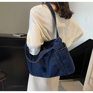 Detail of a large capacity washed navy denim tote bag shown worn by a model from behind