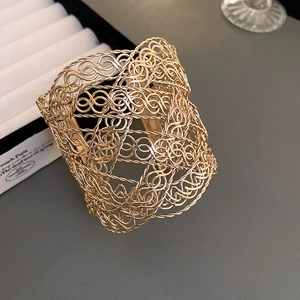 Vue détaillée de la texture métallique tissée creuse sur un bracelet large doré minimaliste
