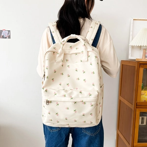 Close-up of cream floral backpack with pink flower patterns on canvas fabric