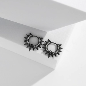 Close-up of black punk rivet hoop earrings with sparkling white stones and spikes