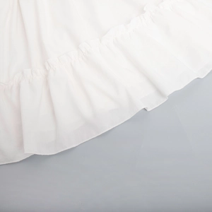 Detailed close-up of white chiffon dress hem featuring elegant ruffle edge layers