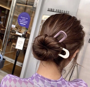 U-shaped hair pins in purple and white resin shown in a real-life bun styling view