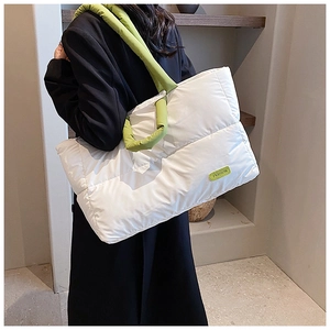 Détail du sac cabas matelassé blanc avec étiquette en caoutchouc vert fluo et anses