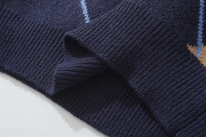 Nahaufnahme der dunkelblauen Strickjacke mit Rautenmuster und gerippter Saumstruktur