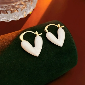 Vue macro de boucles d'oreilles en cœur avec texture marbre blanc et métal doré
