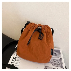 Detail of orange brown nylon bucket bag with drawstring closure and black strap