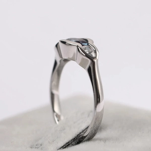 Macro side view of a geometric silver ring with oval blue gem and side stones
