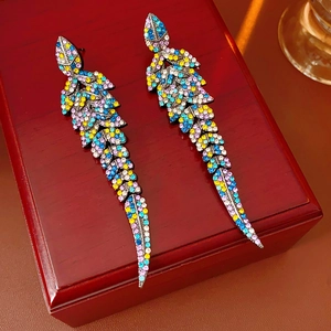 Détail de boucles d'oreilles plumes vintage en argent avec strass colorés sur boîte rouge