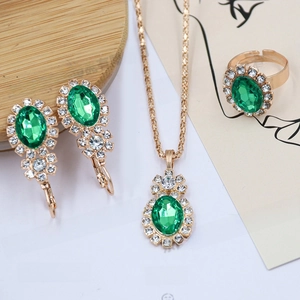 Close-up of green rhinestone necklace, earrings and ring jewelry set on wooden base