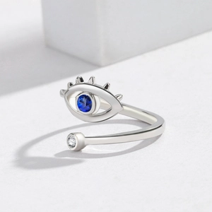 Macro shot of silver evil eye open ring with blue stone and fine metal eyelash details
