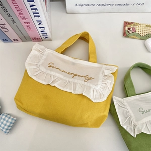 Close-up of canvas lunch bags with white ruffle trim and Summerparty embroidery detail