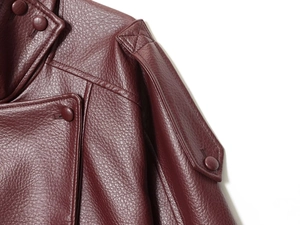 Detailed macro shot of burgundy leather jacket featuring stand collar and epaulette buttons
