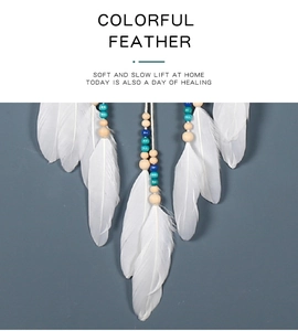 Close-up of bohemian white feathers with blue and wooden beads hanging on a wall