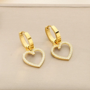Gros plan de boucles d'oreilles cœur en or ornées de diamants pavés et de perles