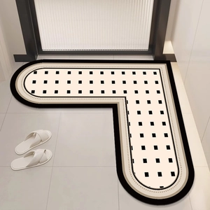 L-shaped non-slip beige bathroom rug with black square pattern on white tiles