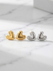 Close-up of heart-shaped stainless steel earrings with hammered texture in gold and silver