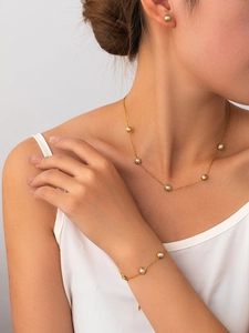 Close-up of golden titanium necklace and pearl bracelet set worn by a female model