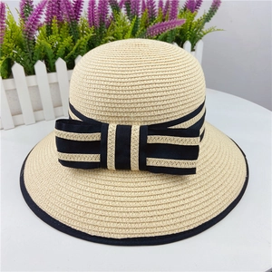 Close-up of beige woven straw sun hat with black and white striped bow detail