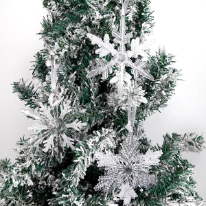 Detail of transparent acrylic snowflakes with silver glitter hanging on a snowy tree