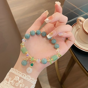 Primer plano de una elegante pulsera de jade violeta con cierre de seguridad verde en la muñeca