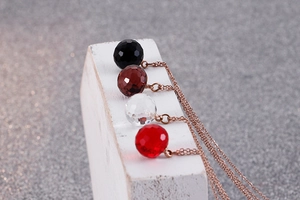 Macro detail of multi-faceted crystal ball pendants on rose gold necklaces in four colors