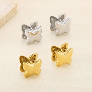 Minimalist 3D butterfly stud earrings in gold and silver finish on a stone platform