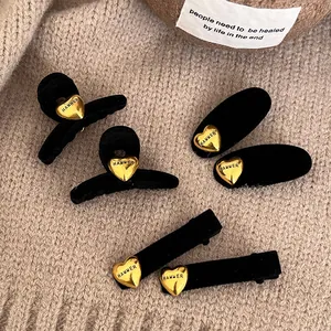 Dettaglio molletta per capelli in velluto nero con ciondolo a cuore dorato inciso