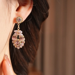 Close-up of vintage style circular gold earrings with pink and purple crystals on model